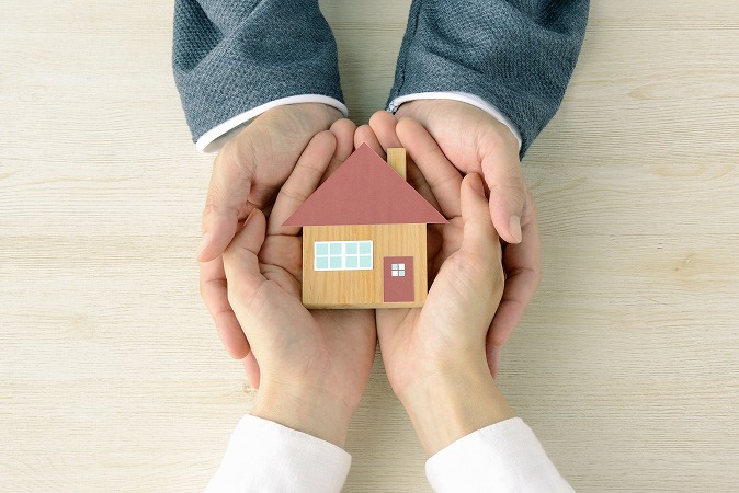 家の模型を包み込む手